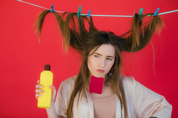 Woman with playful hairstyle holding hair care product