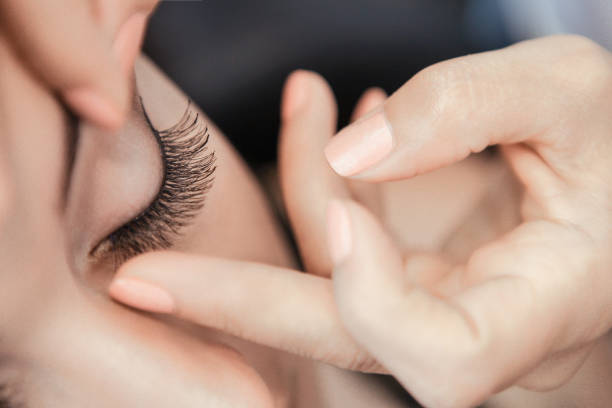 Close-up of woman touching her eyelashes with fingertips.